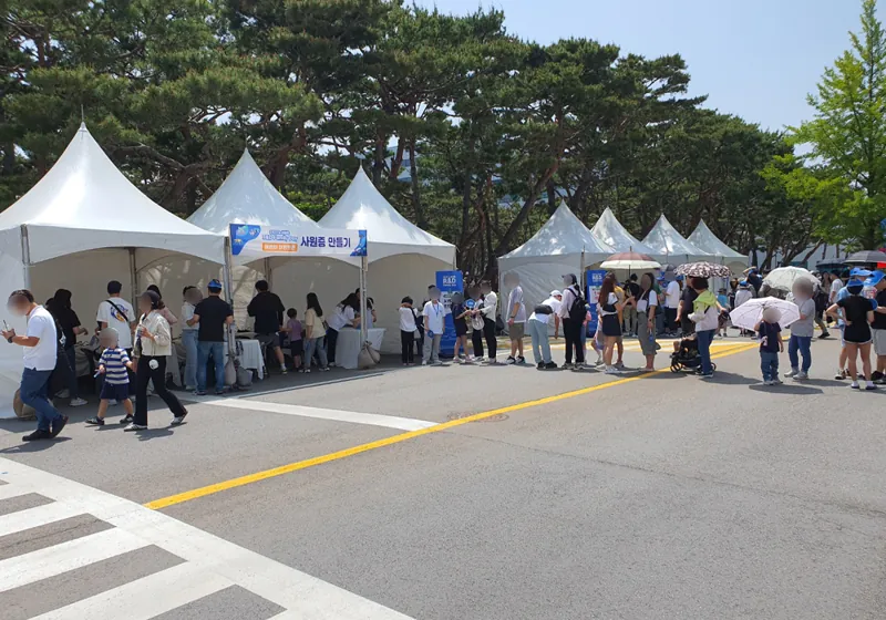 야외 행사장에 늘어선 흰 천막 부스와 사원증 발급을 기다리는 줄