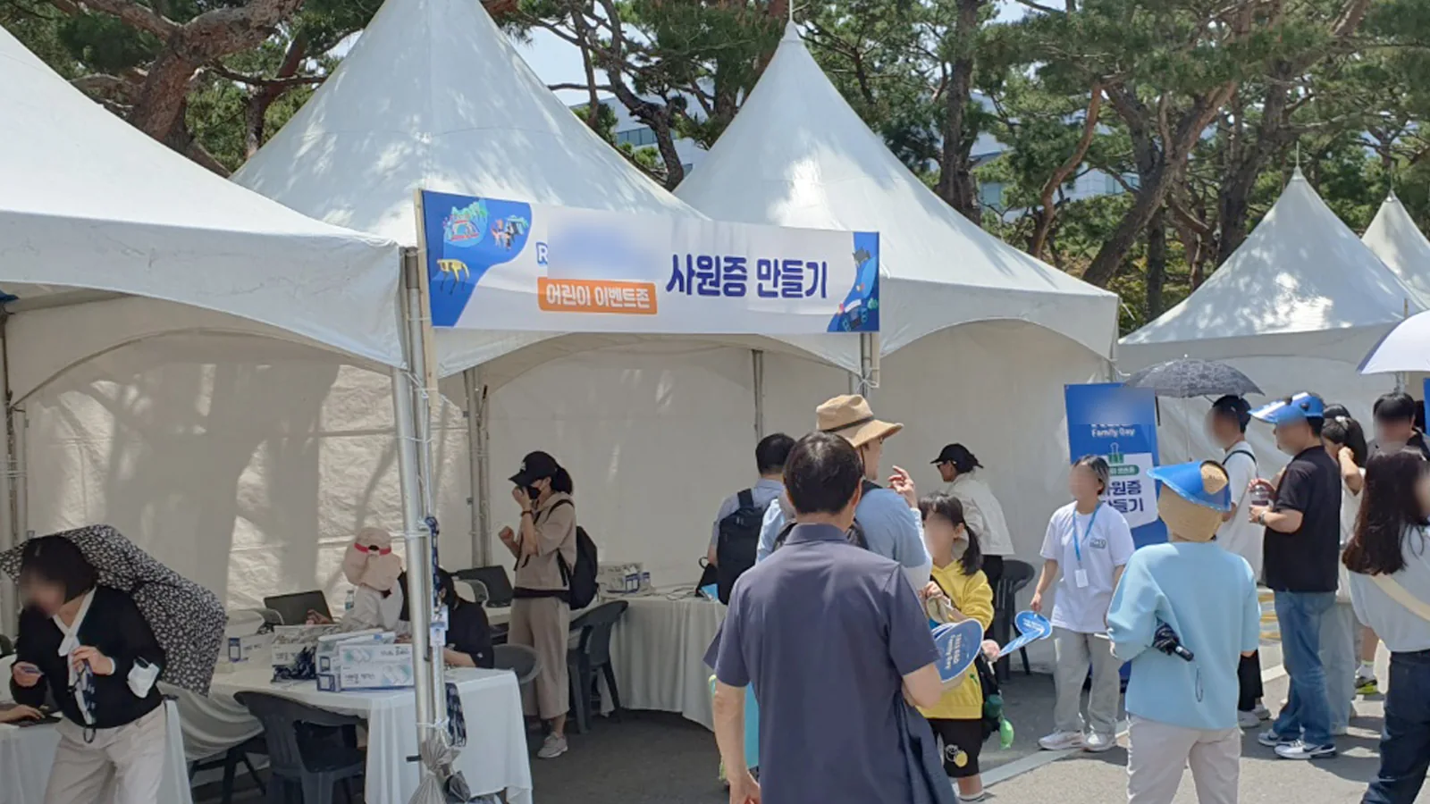 야외 기업 행사장의 사원증 만들기 천막 부스와 참가자들